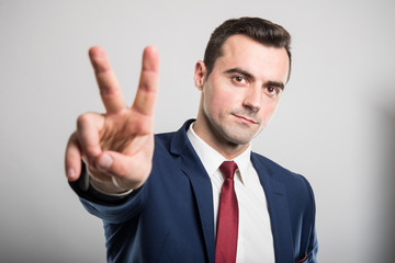 Portrait of young attractive business man showing peace gesture