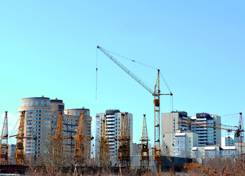Working tower crane on the background of residential houses and non-working cranes on a clear day