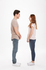 Full length photo of beautiful caucasian couple 20s man and woman wearing beige t-shirts posing together on camera standing face to face, over white background