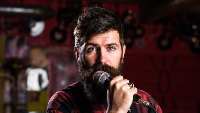 Man with calm face holds microphone, singing song,