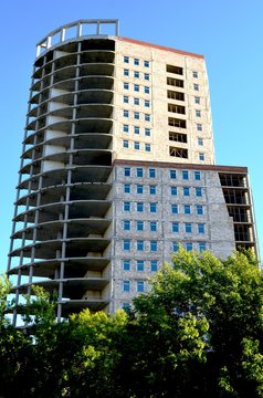 high building of concrete against the blue sky and trees