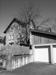Moderne Doppelgarage mit Pultdach vor einem alten Wohnhaus mit Holzzaun in Heidenoldendorf bei...