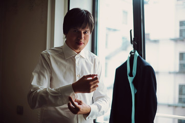 Grooms morning preparation, handsome groom getting dressed and preparing for the wedding, wearing a cufflinks