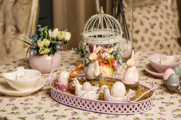 Beautiful Easter pastel decorations with table setting. Porcelain rabbits and Easter eggs.