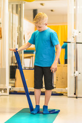 Junge im Physiostudio trainiert mit einem Physiotape