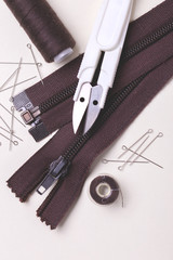 Sewing pins, scissors, zipper and plastic bobbin with colour threads