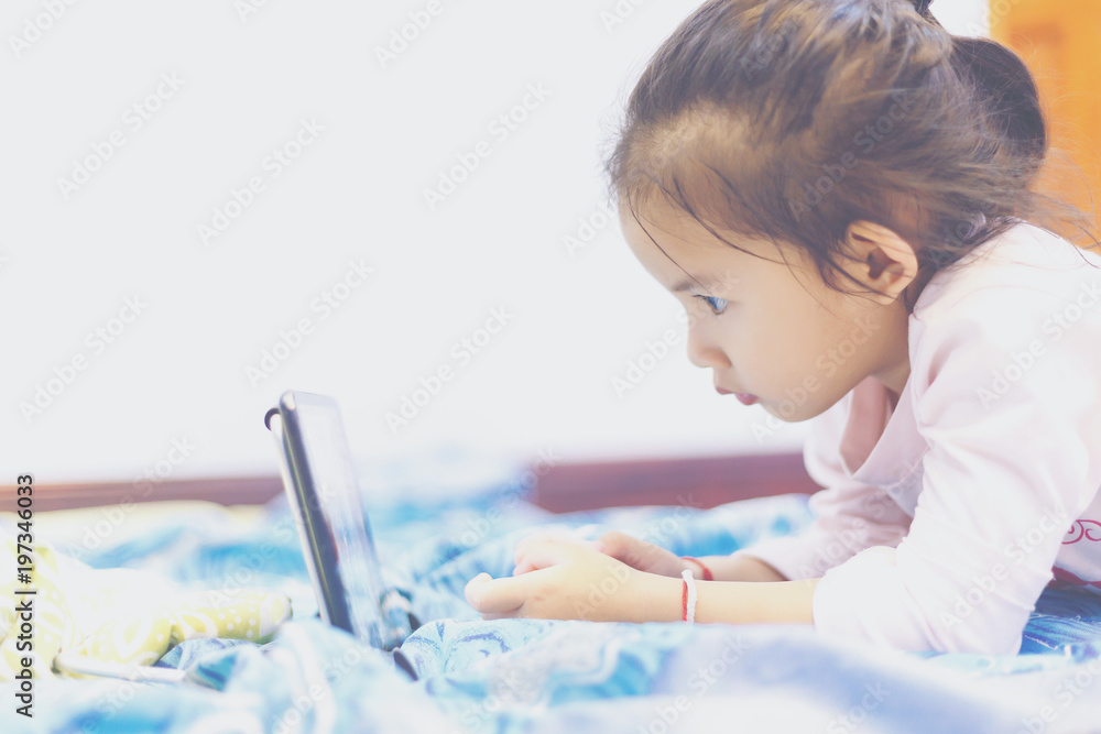 Wall mural Child's watching a learning a lesson in tablet on the bed before bedtime.