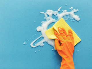 Hand in glove washing glass surface with rag and cleaning foam