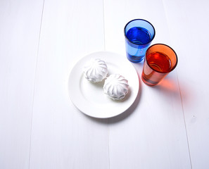 two colorful cups of water and a white plate on white wooden background