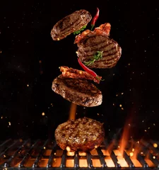 Keuken foto achterwand Grill / Barbecue Stukjes gehakt voor hamburgers die boven de grill vliegen