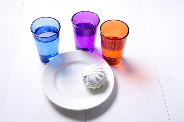 three multi-colored glass and white plate on white wooden background