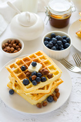 Healthy breakfast. Belgian waffles with butter, blueberry and nuts on white tablecloth. Selective focus