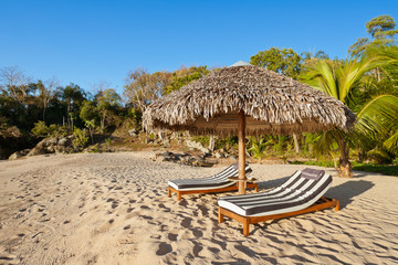 Deckchairs under straw  umbrella