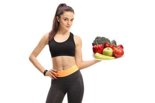 Fitness girl holding a plate of vegetables and fruit