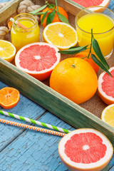 Different fruits and glass with fresh orange juice, wooden background