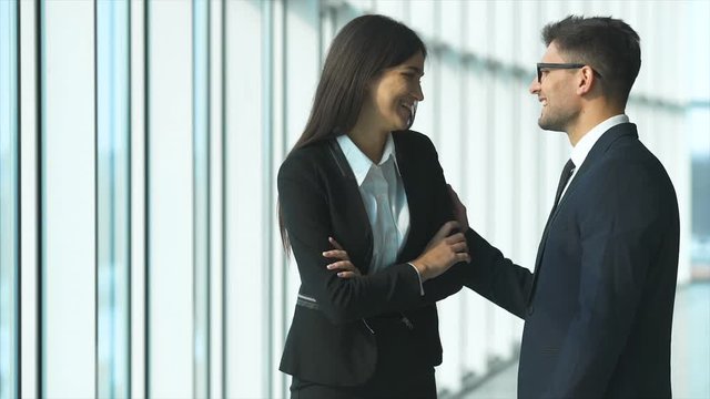 The business woman and a man talk and thumb up in the office hall. slow motion