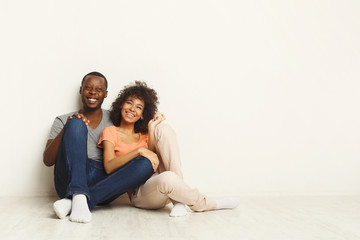Fototapeta na wymiar African-american couple hugging, sitting on floor