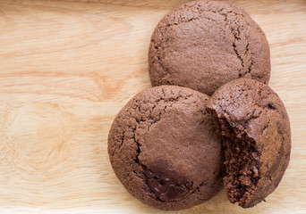 Homemade soft dark chocolate brownie cookies placed on a wooden plate. Close Up cookies are bitten. Look good and delicious.