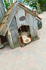 Toy dog ​​in wooden booth in courtyard of  house. Wooden house for small dog.