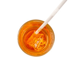 Orange carbonated drink in a glass with straw and ice, overlooking the white background.