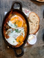 Pretty brunch dish, traditional Middle Eastern meal, Turkish eggs, sourdough toast and butter on china plate