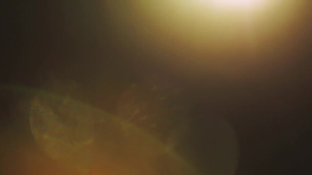 Warm moving light pulses and glows. Dark background. Real lens flare and light leak.