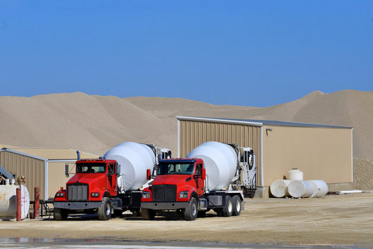 two cement mixer trucks waiting to be loaded
