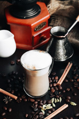 Cup of delicious latte coffee and jezve on black table