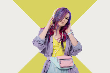 fashionable young woman with colorful hair in purple trench coat listening music with headphones