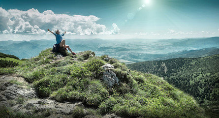 Woman hiking in mountains at sunny day time.