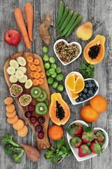Fresh high fibre health food concept with fruit and vegetables high in antioxidants, anthocyanins and vitamins. Rustic background, top view.