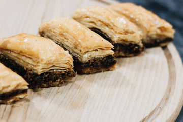 Baklava sweet dessert on wooden board. Pastry made of layers of filo filled with chopped nuts and...