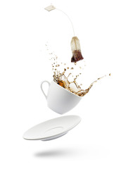 cup of tea falling with tea bag splashing on white background