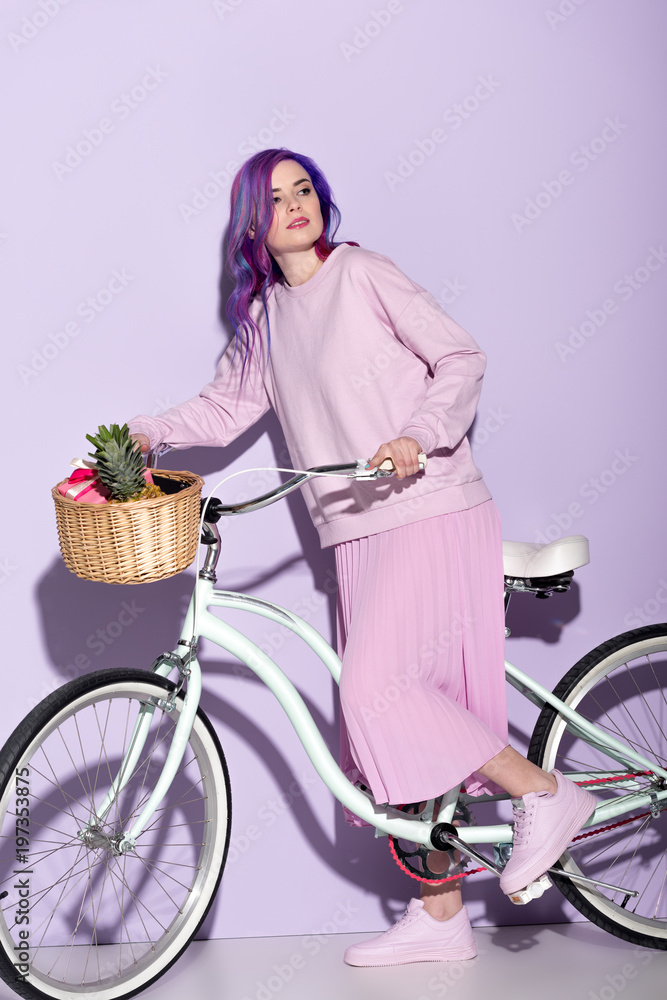 Wall mural attractive woman in pink clothing on bicycle with pineapple and bananas in basket