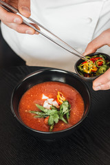 Woman cooking delicious tomato soup with parsley