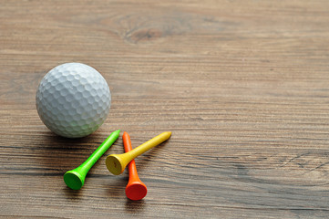 A golf ball with tee's isolated on a wooden background