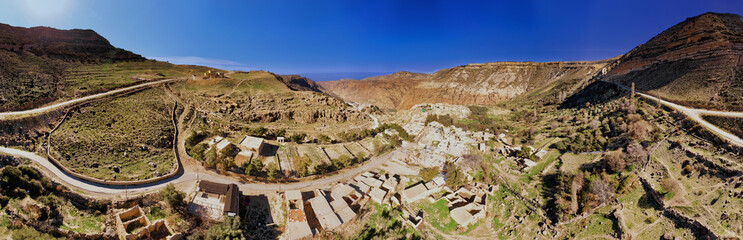 Composite high-resolution panorama of the Dana Village narby the Dana Reserve, a 1000-metre deep valley cut in the south-western mountainous region of the Kingdom of Jordan. - obrazy, fototapety, plakaty