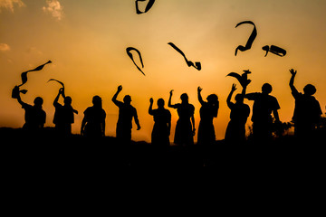 Silhouette group friends graduation holding papers playing throwing at sunset time.