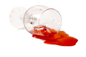 Опрокинутый фужер с красным коктейлем и льдом на белом фоне