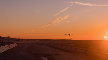 The big airliner landed on the sunset track, the backlit aircraft in orange and golden tones.