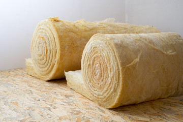 roll of mineral wool lying on the wooden floor - obrazy, fototapety, plakaty