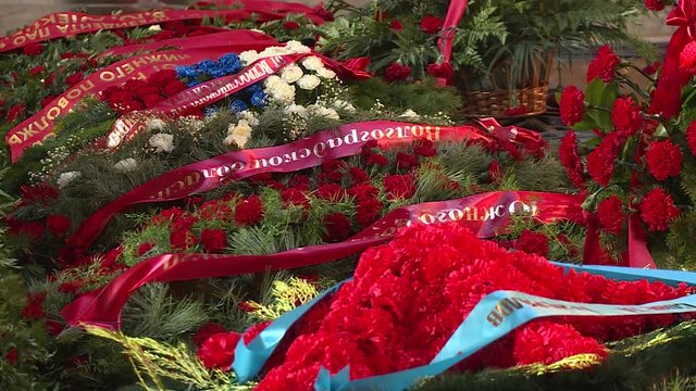 Red flowers lie on memorial. Tribute to the memory of victims in the Great Patriotic War. Grave of died soldiers. Russian letters on the wreaths of memory