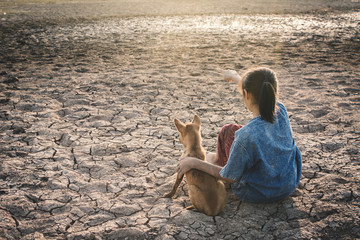 Sad girl tired and exhausted with dog on cracked dry ground , Concept drought and shortage of water crisis