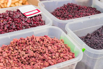 dried berries in plastic containers displayed on street market