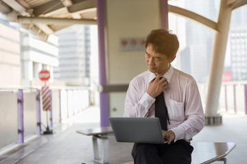 Fototapeta premium Asian businessman working on train station