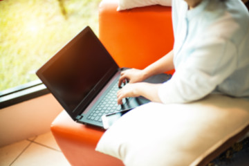 The blurry light design background of lady is using laptop for working and doing online business