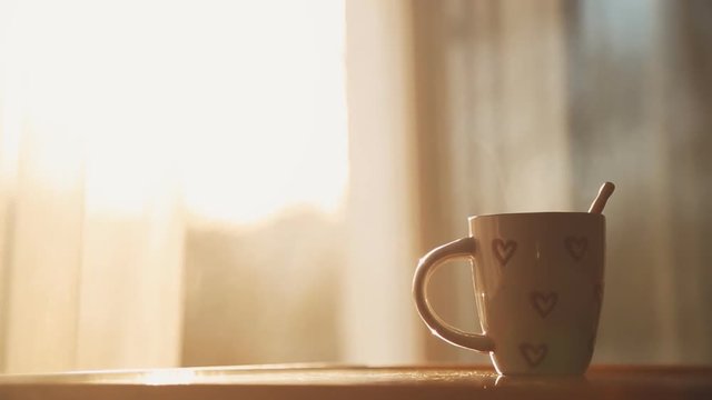 Cup of hot tea at window side abstract blur background.