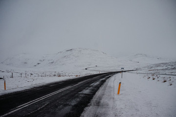 A windy road in Iceland, leading through a mountain plateau completely covered in snow