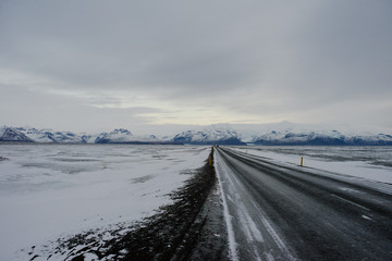 A straight road leading through a snowy field in Iceland