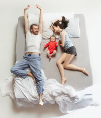 Top view of happy family with one newborn child in bedroom.